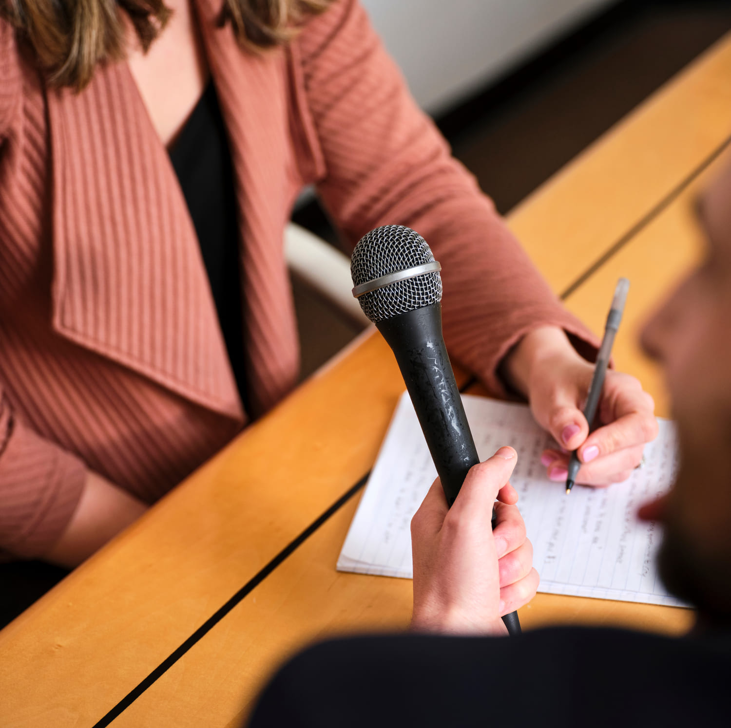 Close up of a microphone during an interview and a woman writing on a notepad