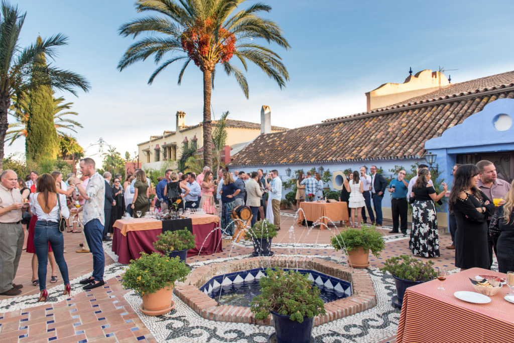 Attendees gather next to a fountain for an evening event in Marbella, Spain