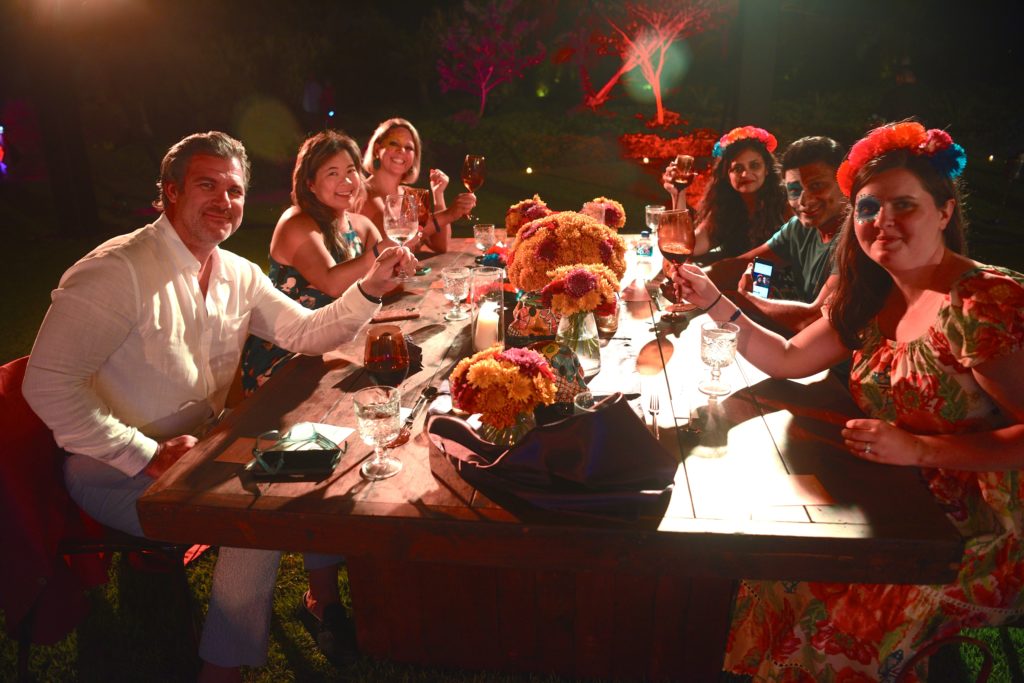 Guests raise a glass around at table at a Día de Muertos evening event