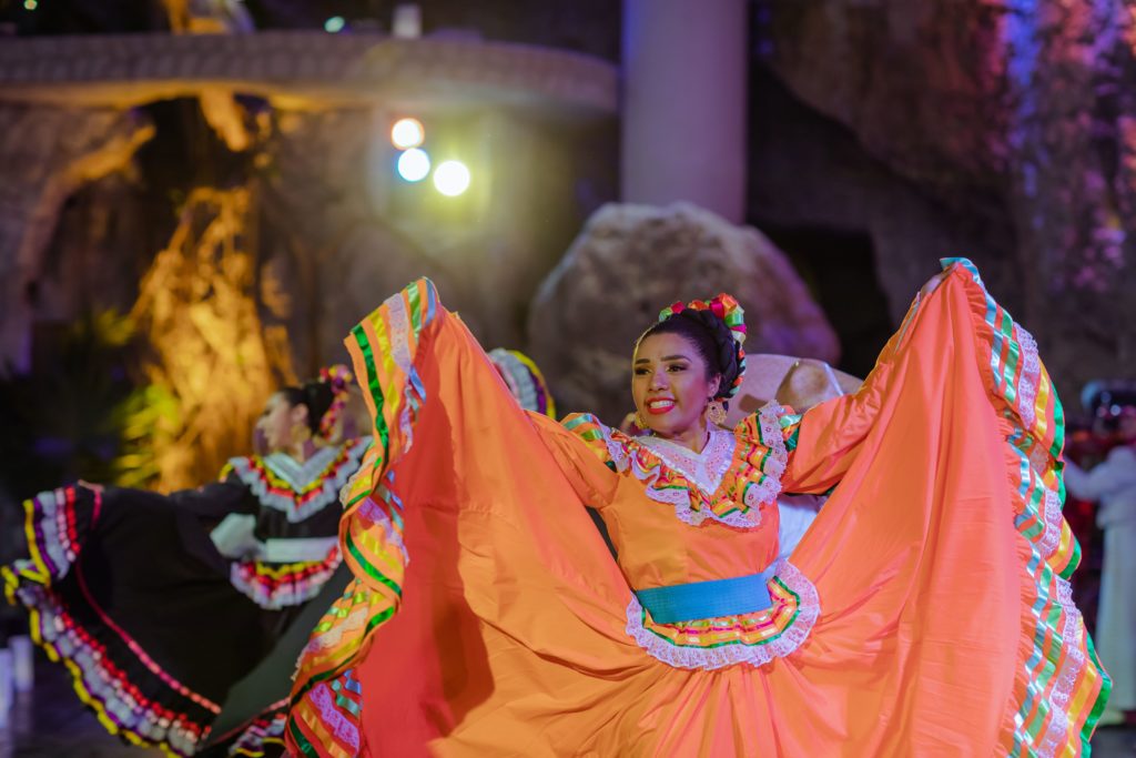 Dancers in traditional mexican dresses dance on stage