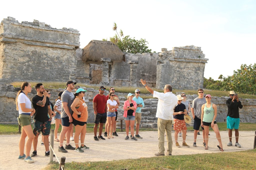 A tour guide speaks to a private corporate group at Tulum