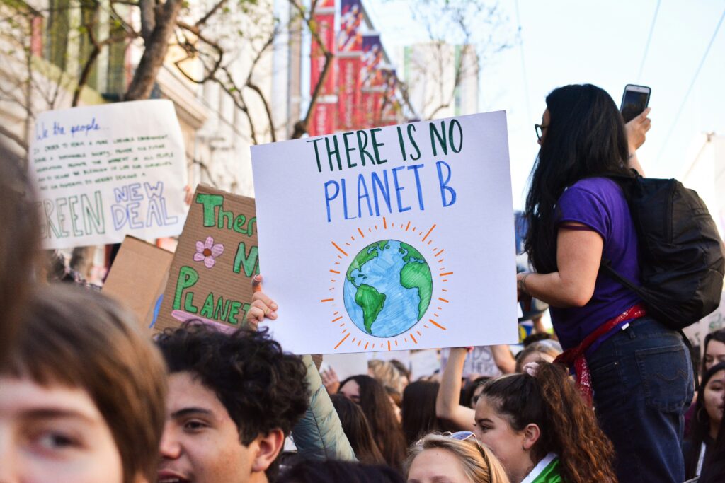 environmental protesters, one with a sign that says "there is no planet b" with a drawing of the earth
